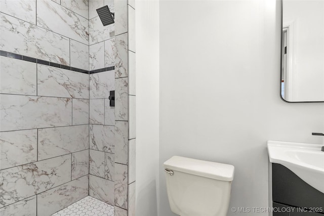 bathroom with vanity, toilet, and a tile shower