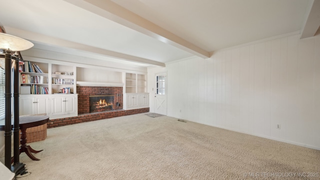 carpeted living room with a brick fireplace, built in shelves, and beamed ceiling