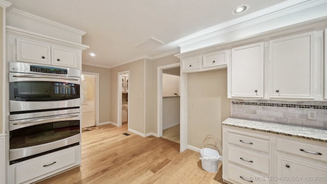 kitchen featuring white cabinetry, backsplash, light stone countertops, and stainless steel double oven