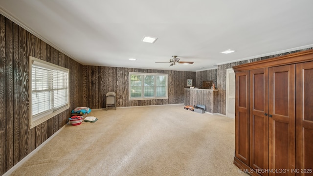 interior space featuring plenty of natural light, ornamental molding, ceiling fan, and carpet