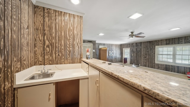 kitchen with light stone counters, sink, and ceiling fan