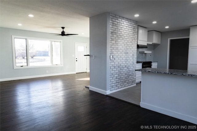 kitchen featuring recessed lighting, dark wood-type flooring, white cabinetry, baseboards, and dark stone counters