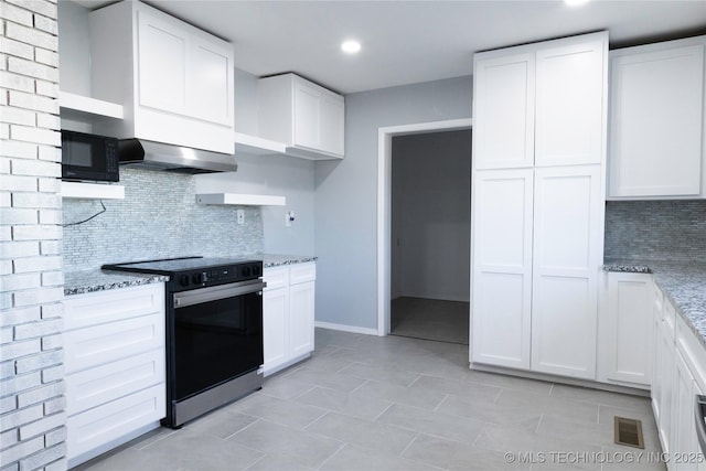 kitchen with wall chimney range hood, range with electric cooktop, black microwave, and light stone counters