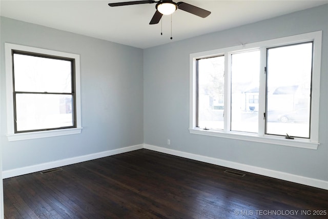 unfurnished room featuring a healthy amount of sunlight, baseboards, and dark wood-type flooring