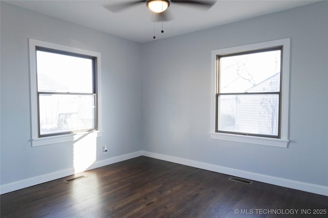 empty room with baseboards, visible vents, and dark wood-type flooring