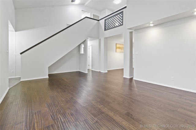 unfurnished living room featuring dark hardwood / wood-style flooring and high vaulted ceiling