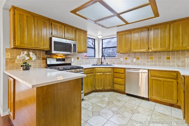 kitchen featuring sink, decorative backsplash, kitchen peninsula, and appliances with stainless steel finishes