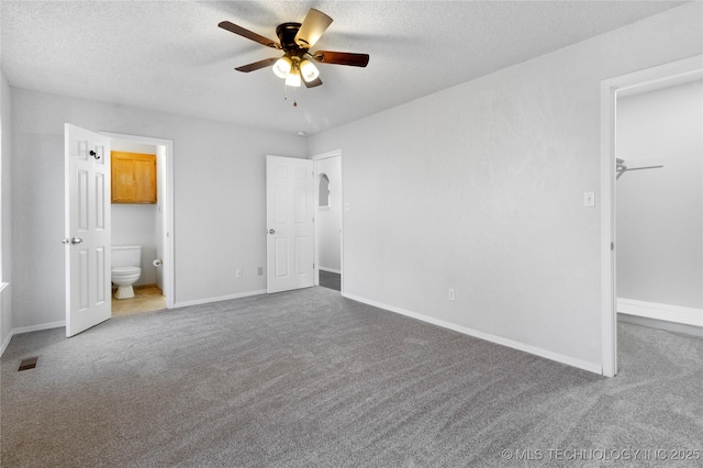 unfurnished bedroom with a spacious closet, connected bathroom, a textured ceiling, and carpet flooring