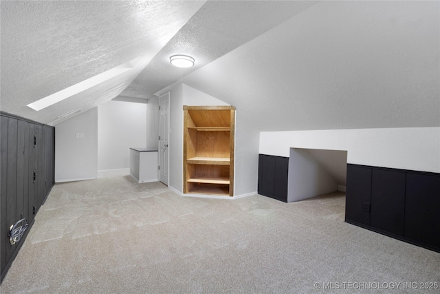 additional living space with lofted ceiling, light carpet, and a textured ceiling