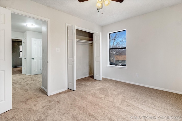 unfurnished bedroom featuring ceiling fan, light colored carpet, a closet, and a textured ceiling