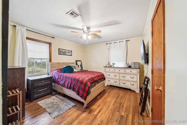 bedroom featuring wood-type flooring, ornamental molding, and ceiling fan