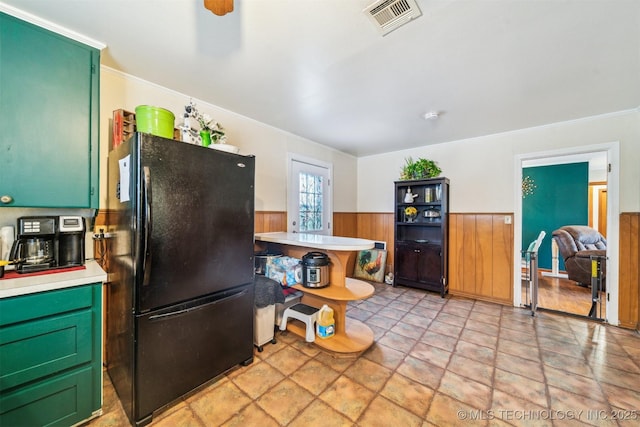 kitchen with crown molding, green cabinetry, and black fridge