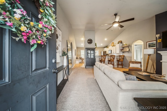 carpeted living room with lofted ceiling, ceiling fan, arched walkways, and recessed lighting