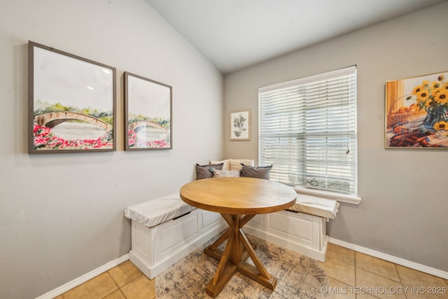 dining area featuring vaulted ceiling, light tile patterned floors, breakfast area, and baseboards