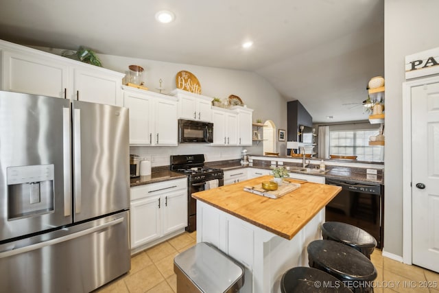 kitchen featuring a center island, a breakfast bar area, white cabinetry, a peninsula, and black appliances