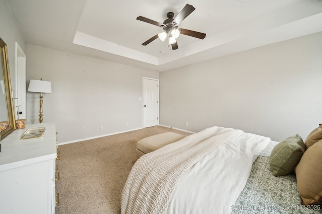 bedroom with carpet floors, baseboards, a raised ceiling, and a ceiling fan