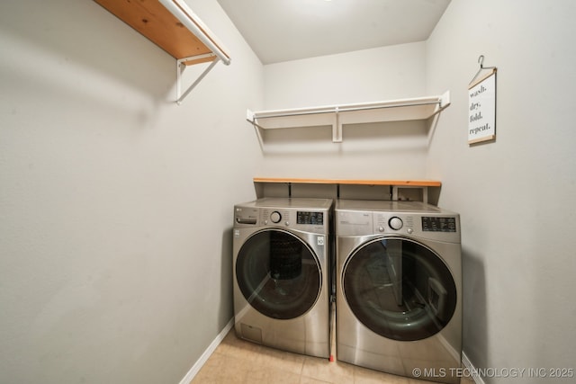 laundry area with light tile patterned floors, laundry area, washing machine and clothes dryer, and baseboards