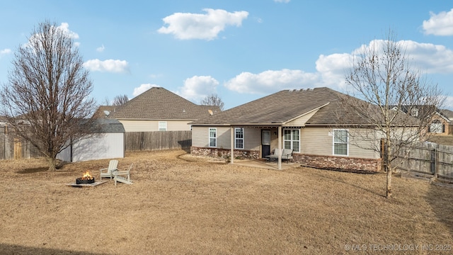 back of property with brick siding, a yard, an outdoor fire pit, a patio area, and fence private yard