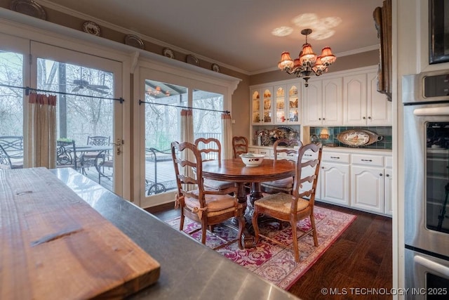 dining space featuring dark wood-style flooring, an inviting chandelier, and crown molding