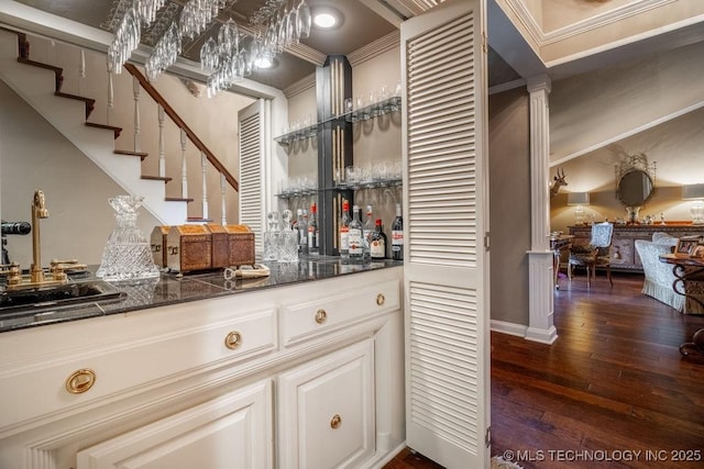 bar featuring a sink, indoor bar, ornamental molding, and dark wood-style floors
