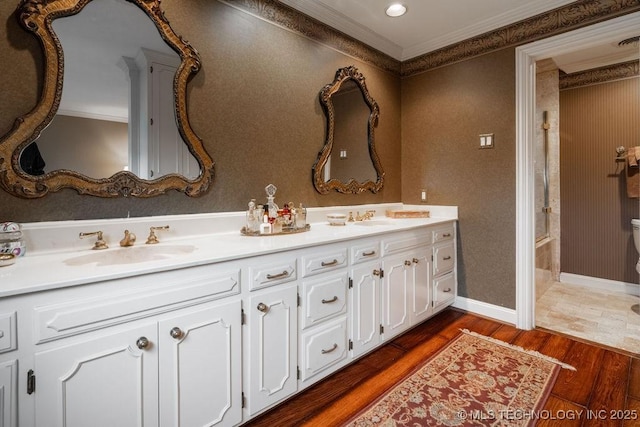 bathroom with a sink, ornamental molding, double vanity, and wood finished floors