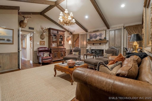 living area featuring visible vents, a notable chandelier, a fireplace, wood finished floors, and vaulted ceiling with beams