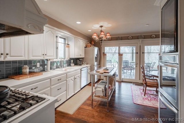 kitchen with a sink, white cabinetry, a chandelier, and stainless steel appliances