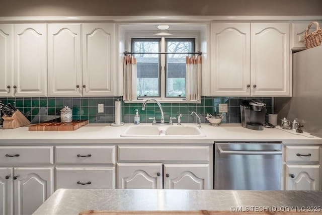 kitchen featuring stainless steel dishwasher, white cabinetry, a sink, and backsplash
