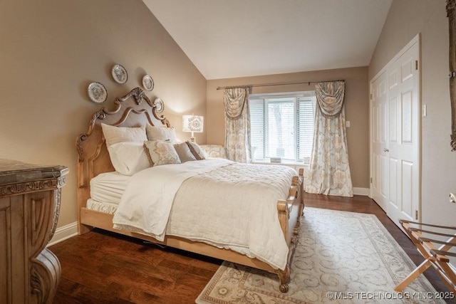 bedroom featuring dark wood-style floors, baseboards, and vaulted ceiling