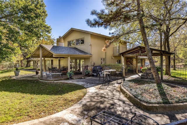rear view of house with a yard, fence, a shingled roof, and a patio