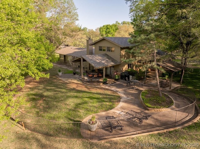 rear view of house with a lawn, a patio area, stairs, a chimney, and a shingled roof