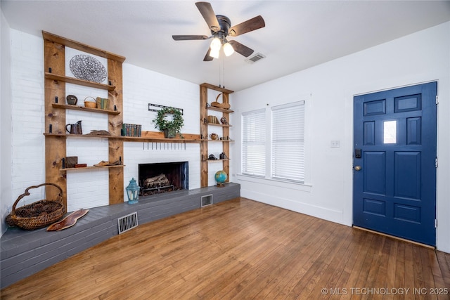 unfurnished living room featuring hardwood / wood-style flooring, a brick fireplace, and ceiling fan