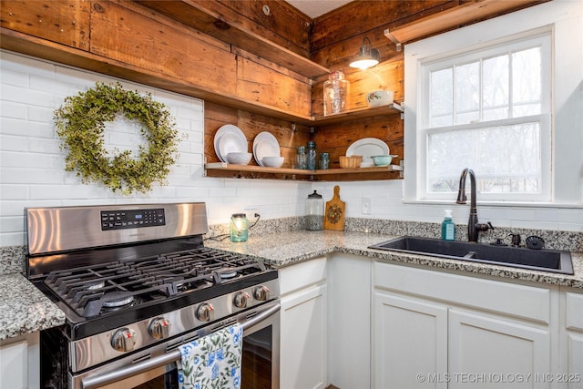 kitchen featuring white cabinetry, sink, light stone counters, and stainless steel gas stove