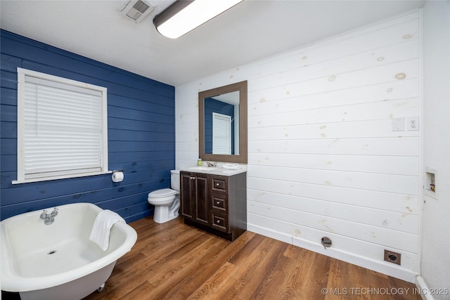 bathroom with wood-type flooring, a tub, vanity, and toilet