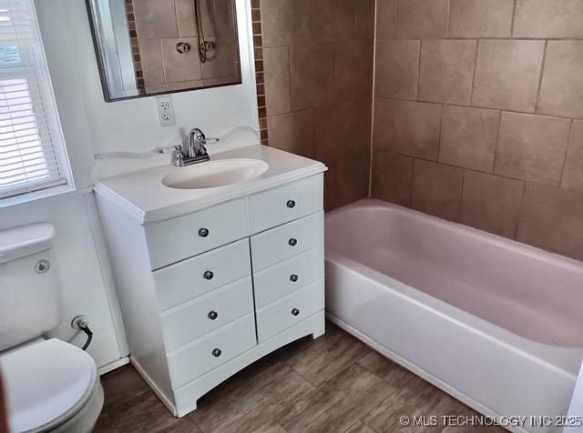 full bathroom with tiled shower / bath combo, vanity, and toilet