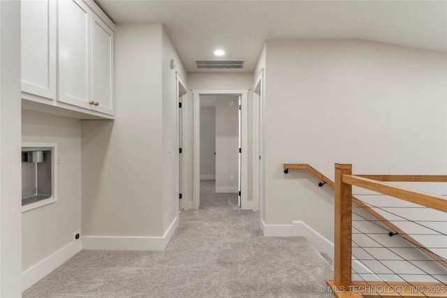 corridor with an upstairs landing, visible vents, light carpet, and baseboards