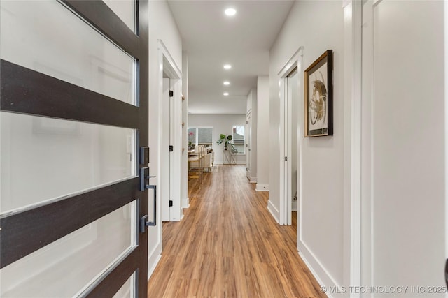 corridor featuring baseboards, recessed lighting, and light wood finished floors
