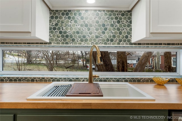 room details featuring white cabinets, light countertops, decorative backsplash, and a sink