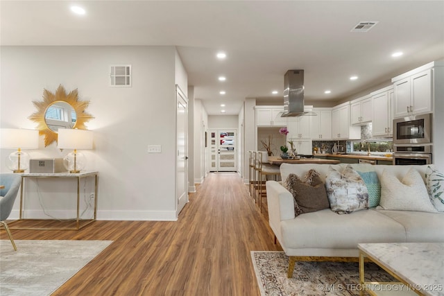 living room featuring recessed lighting, visible vents, baseboards, and light wood-type flooring