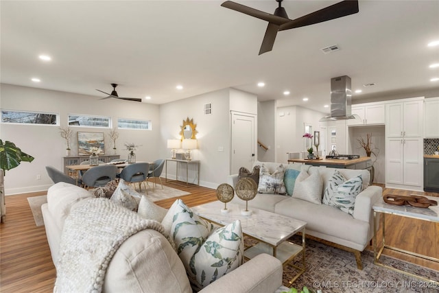living room with visible vents, baseboards, recessed lighting, wood finished floors, and a ceiling fan
