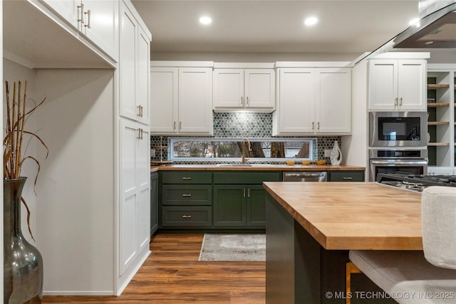 kitchen with wood counters, a sink, appliances with stainless steel finishes, dark wood-style floors, and backsplash