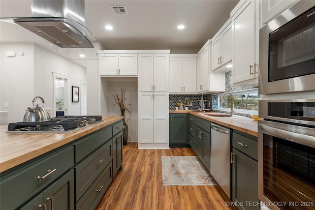 kitchen featuring white cabinetry, stainless steel appliances, butcher block countertops, and a sink