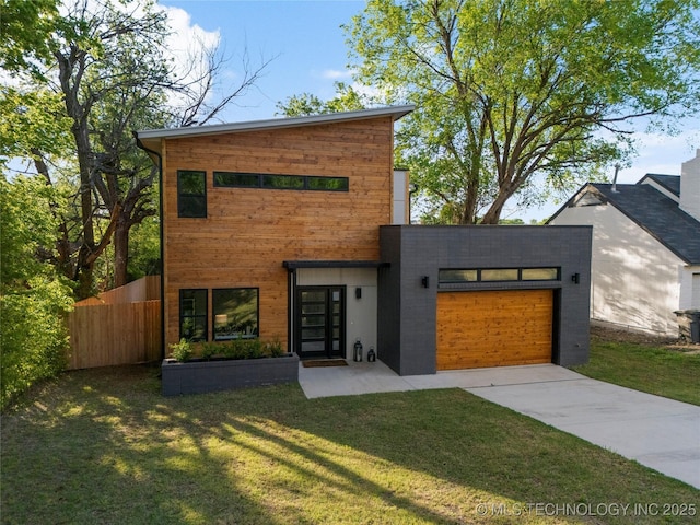 modern home featuring a garage, fence, a front lawn, and concrete driveway