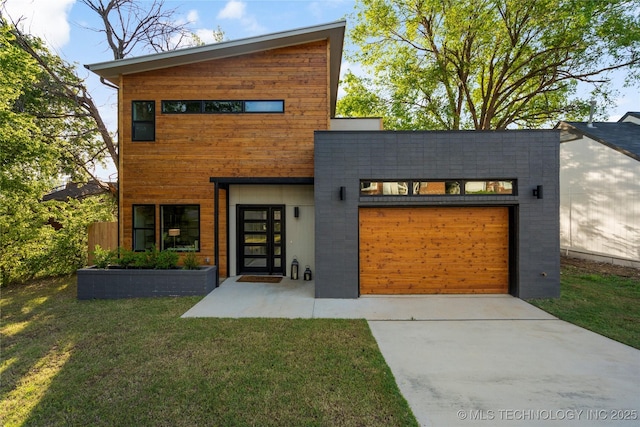 modern home with concrete driveway, a garage, and a front lawn