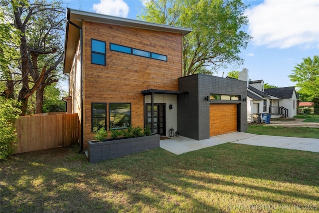 modern home featuring a chimney, fence, driveway, a front yard, and an attached garage