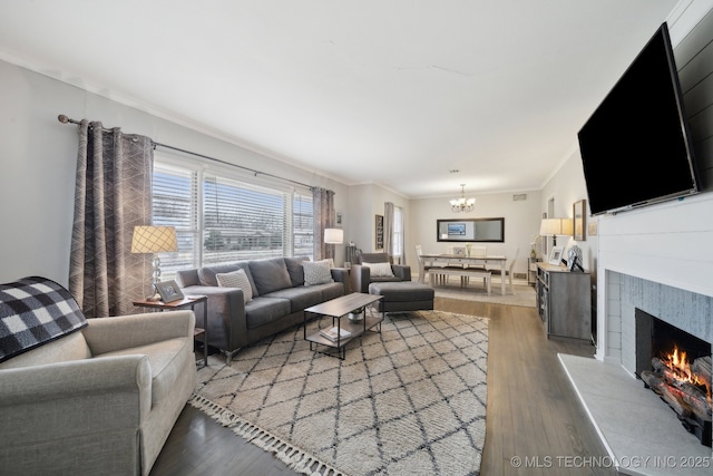 living room featuring hardwood / wood-style flooring, a tile fireplace, crown molding, and a chandelier