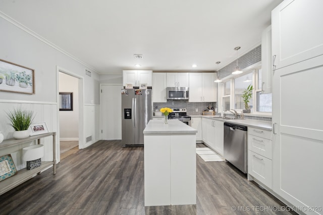 kitchen with pendant lighting, stainless steel appliances, a kitchen island, and white cabinets