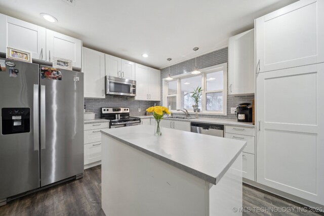 kitchen with stainless steel appliances, white cabinetry, and pendant lighting