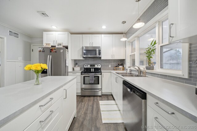 kitchen featuring appliances with stainless steel finishes, sink, pendant lighting, and white cabinets