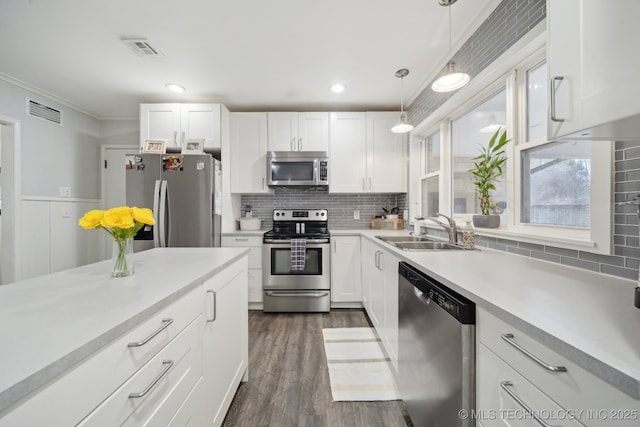 kitchen featuring white cabinetry, appliances with stainless steel finishes, sink, and hanging light fixtures